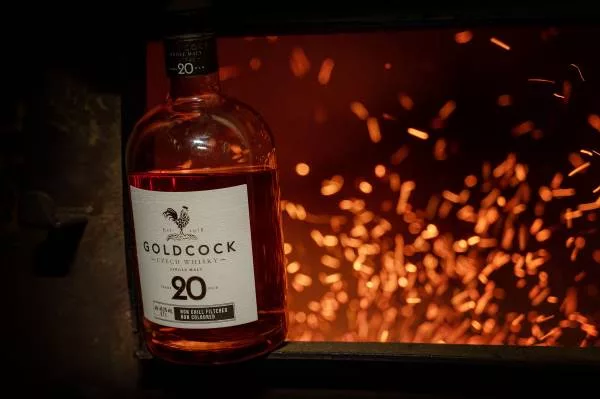 Collection of Gold Cock Czech whisky bottles featuring 10 Year, Peated, Blended and 20 Year expressions displayed outdoors.