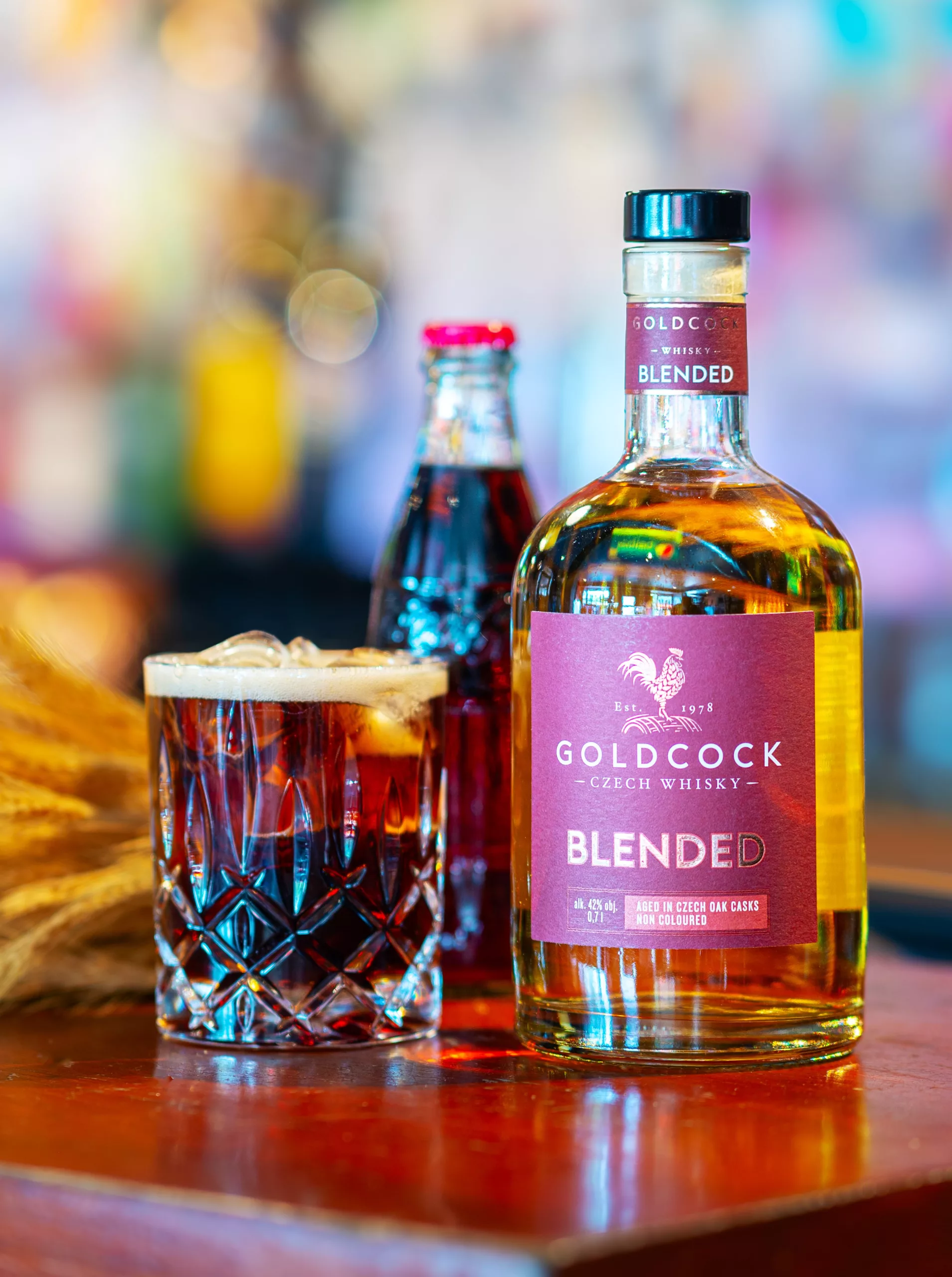 Gold Cock Blended Czech whisky bottle served with a whisky cocktail on a bar, showcasing the brand's premium blended whisky.