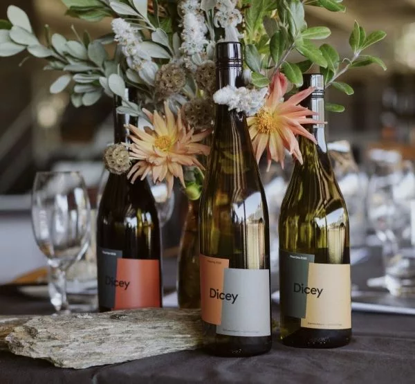 Dicey wine bottles styled with fresh flowers on a dining table, creating an elegant wine presentation.